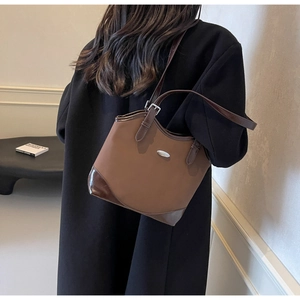 Detail of brown nylon tote bag with leather trim and metal ornament on textured background