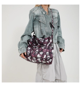 Detail of canvas bag featuring skull and pink rose prints with wide crossbody strap