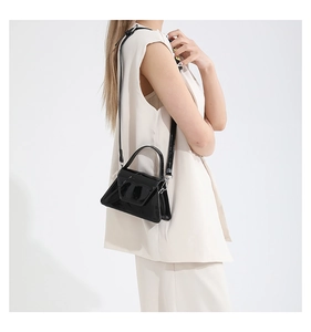 Side view of a glossy black patent leather mini handbag with a trapezoidal structure