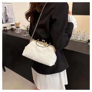 Detail of white lace embroidery evening bag with vintage gold metal clasp and chain