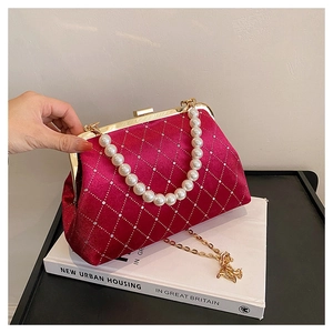 Macro shot of burgundy velvet shell bag with diamond stitching and pearl handle