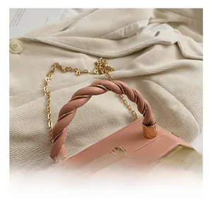 Detail view of pink leather box bag with twisted handle, gold chain and metallic clasp