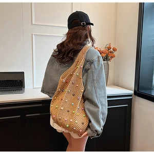 Detail of woven straw tote bag with colorful pearl accents on a denim jacket model