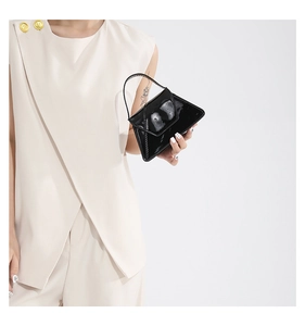 Detail of elegant black patent leather handbag with glossy trapezoidal flap and top handle