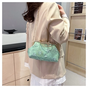 Detail of mint green lace evening bag with 3D floral appliqués and butterfly clasp