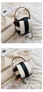 Detail der Mini-Web-Eimertasche mit schwarz-weißen Streifen und braunem Ledergriff
