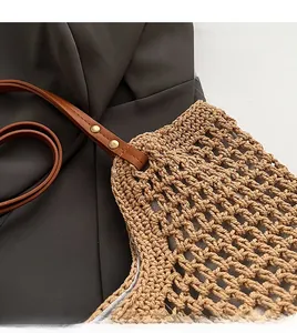 Close-up of handmade woven tote bag with brown leather strap and gold metal rivets