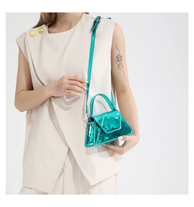 Detailed view of the mini turquoise metallic patent leather handbag with a top handle