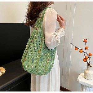 Detail of green knit tote bag featuring colorful bead accents and soft woven texture