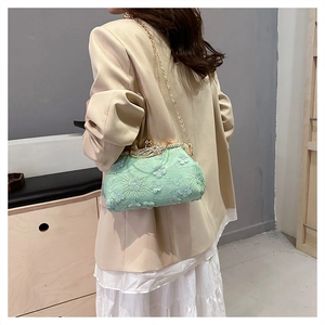 Detail of mint green lace evening bag with 3D flower embroidery and gold chain strap
