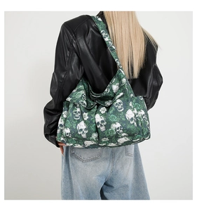 Close-up of green canvas bag featuring white skull and rose prints on a model