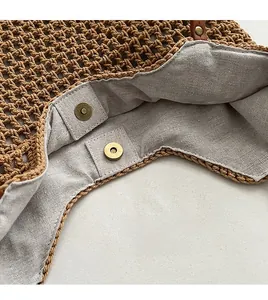 Close-up of brown hand-woven tote bag showing magnetic snap closure and gray cotton lining