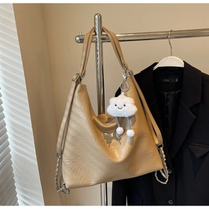 Close-up of beige shoulder bag with silver butterfly charm and plush cloud keychain