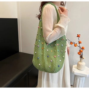 Detail of green knit shoulder bag featuring colorful pearls for a beach vacation style