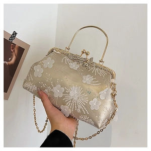 Detailed view of champagne silk evening bag with white floral embroidery and butterfly clasp