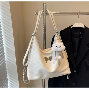 Detail of white PU shoulder bag with silver butterfly charm and plush cloud keychain