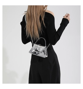 Silver metallic patent leather mini shoulder bag worn by model over a black dress