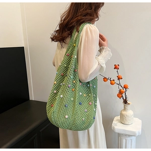 Close-up of green woven tote bag featuring colorful faux pearls and crochet texture