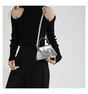 Detail of silver metallic mini handbag with top handle and strap on black outfit
