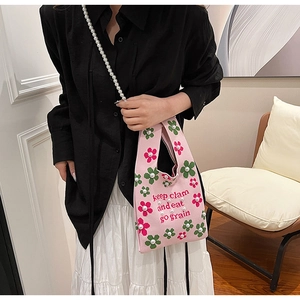Pink knitted bucket bag with floral embroidery and pearl chain strap on model