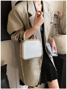 Detail of light blue box bag with gold metal trim and chain strap shown on model