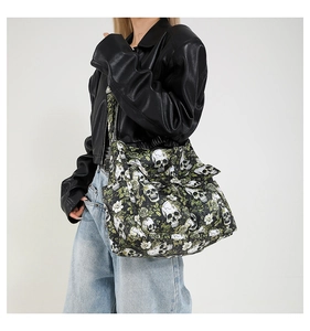 Detail of canvas shoulder bag with gothic skull and green vine floral print on model