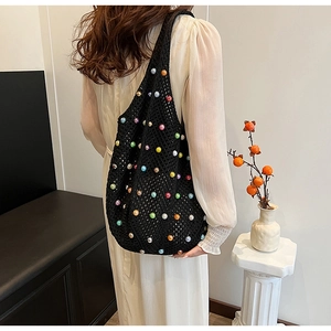 Detail of black crochet tote bag with colorful beads and hollow mesh pattern