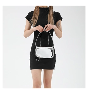 Detail of silver mirror finish shoulder bag with metallic chain strap on black dress