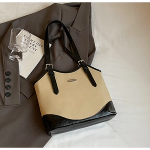 Detail of minimalist beige and black tote bag showing metal buckle and smooth PU leather