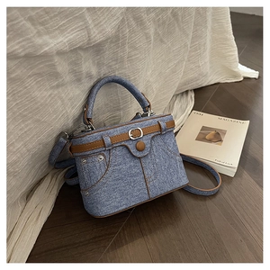 Detailed texture of blue denim and brown leather trim on a creative small square crossbody bag