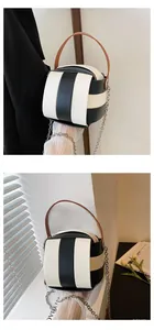 Detail der kugelrunden Beuteltasche mit schwarz-weißen Streifen und Ledergriff