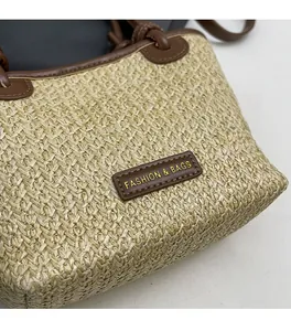 Detailed view of straw weave texture and leather strap on a large tote shoulder bag