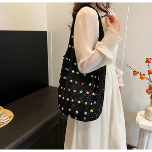 Detail of black crochet tote bag featuring colorful faux pearls on elegant model