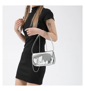 Close-up of silver metallic mirror shoulder bag with bead chain on black dress