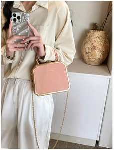 Detail of pink fashion box bag with gold metal frame and stylish chain strap