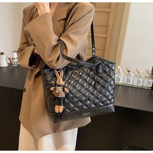 Detail of black quilted tote bag featuring a cute houndstooth rabbit plush charm accessory