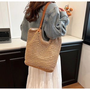 Close-up of handmade woven tote bag featuring hollow knit texture and brown leather strap