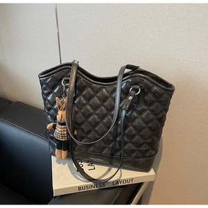 Detail of black quilted tote bag with rabbit charm and FASHION BAG text