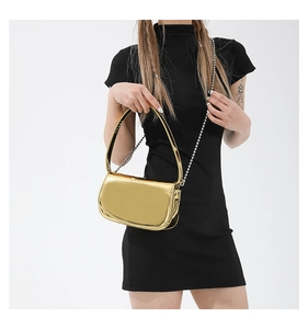Detail of metallic gold glossy shoulder bag featuring chic bead chain and patent finish