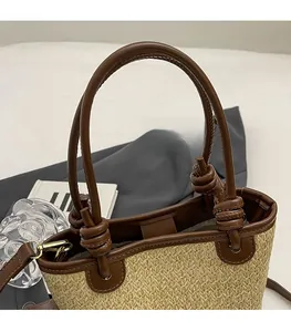 Detail of straw woven tote showing reinforced brown leather handle and fine texture