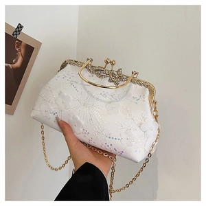 Detail of white lace evening bag with gold butterfly clasp and sequin floral embroidery