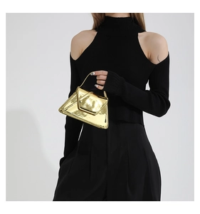 Close-up of a stylish gold patent leather shoulder bag with a modern triangle flap design