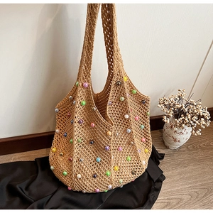 Detail of bohemian woven tote bag with colorful faux pearls and open mesh texture