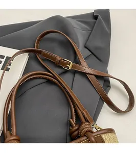 Detail of adjustable leather shoulder strap and woven texture on a brown bucket bag