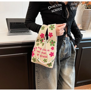 Detail of knitted bucket bag featuring floral patterns and elegant double pearl chain strap