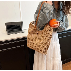 Detail of hand-woven crochet tote bag featuring brown faux leather straps and large capacity