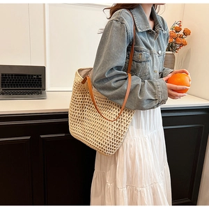 Detail of hand-woven beige tote bag with hollow mesh pattern and brown leather straps