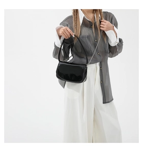 Close-up of black patent leather shoulder bag with a sleek silver chain strap for women