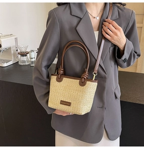 Detail of straw tote bag featuring brown leather straps and fashion label tag