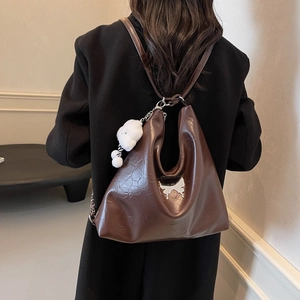 Brown leather hobo bag with silver butterfly and plush charm shown on model's back